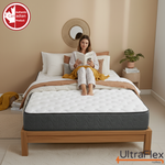 Person reading while seated on an UltraFlex Stellar mattress in a beige bedroom.