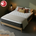Angled bedroom view of the UltraFlex Summit mattress with cream bedding and gold cushions.