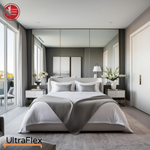 Modern bedroom with a neatly dressed bed, grey bedding and mirrored wall panels.