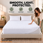 Woman smoothing a white Comfort Living waterproof mattress protector with stretch sides on a bed.