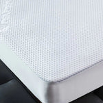 Close-up of a white textured mattress protector fitted over a mattress corner.