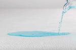 Water poured onto a white mattress protector to demonstrate its waterproof surface.